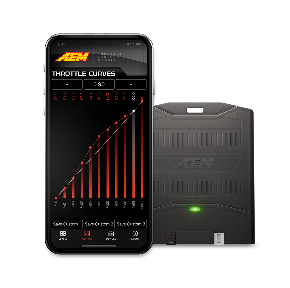 A black automotive electronic device with a green indicator light next to a smartphone displaying an AEM throttle curves app interface, on a solid white background.