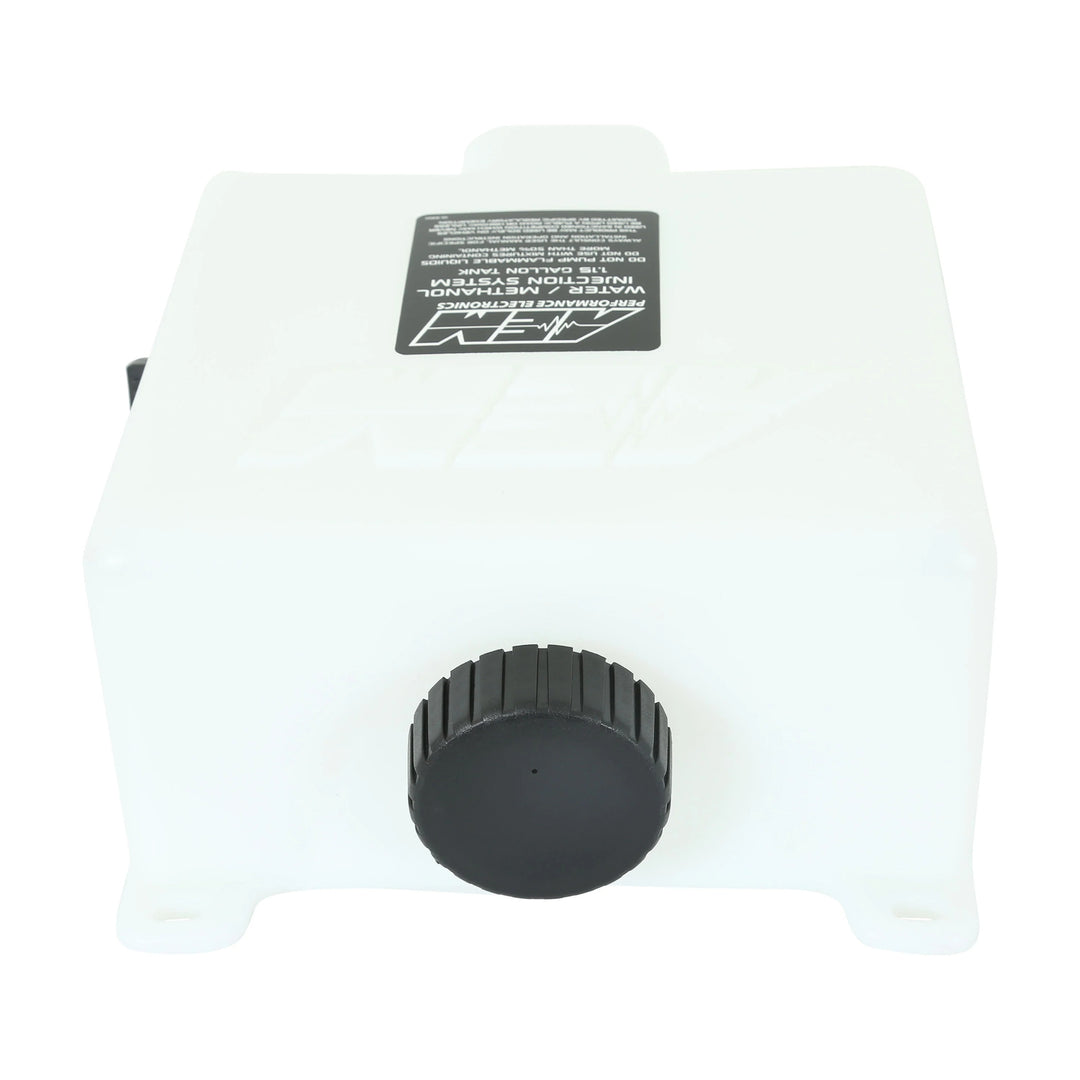A white plastic reservoir tank with a black ribbed cap and a black label on top, photographed against a plain white background.