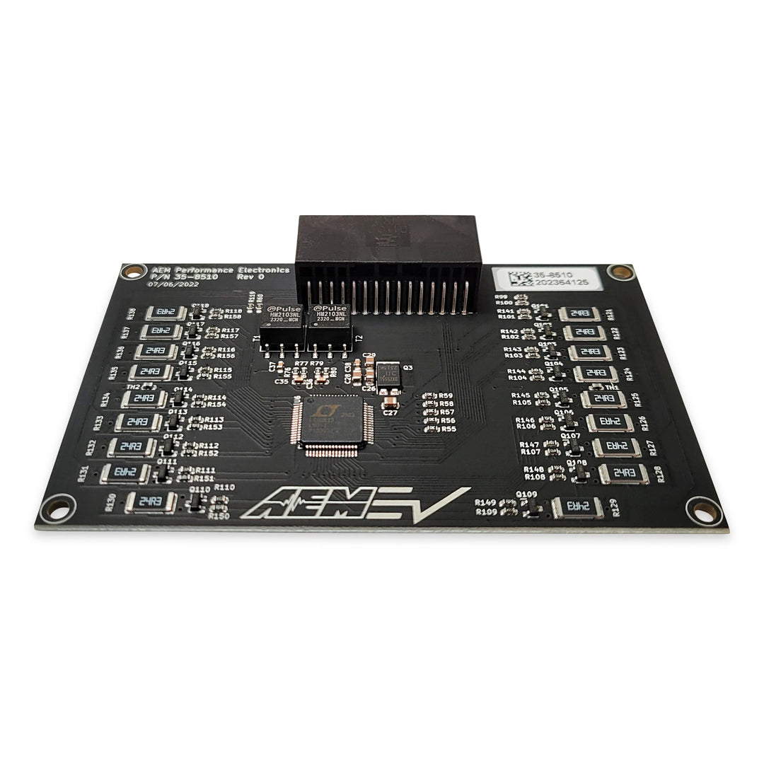 A black automotive electronic control module board with various integrated circuit chips, resistors, and a central black connector block, photographed on a solid white background.
